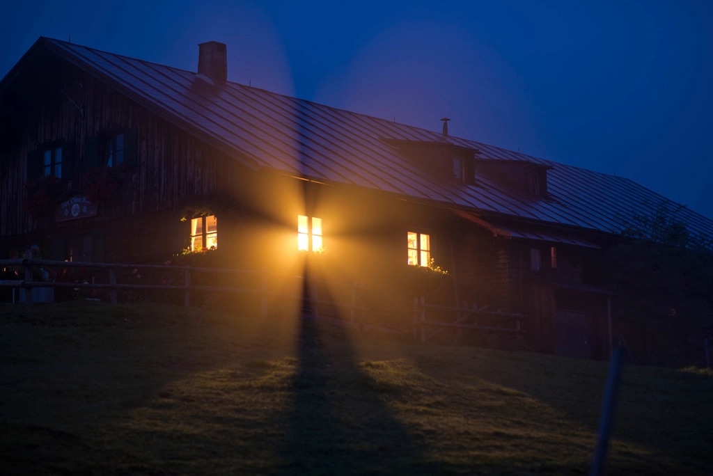 Casa iluminada con luz cálida en sus ventanas durante la noche.